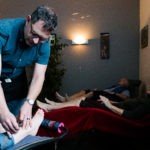 Several people relaxing after receiving acupuncture. Acupuncturist removes needles from a patient in the foreground