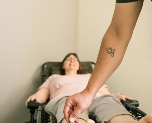 an acupuncturist puts a needle into a patients ankle