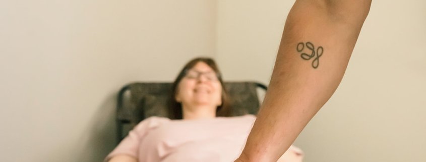 an acupuncturist puts a needle into a patients ankle