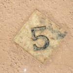 A wooden tile with the number 5 on it.